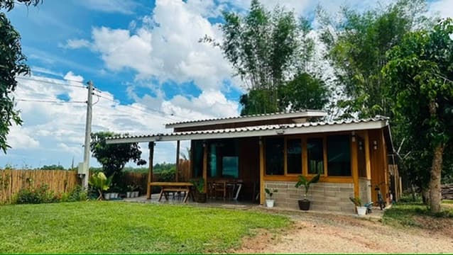 A teak cabin under wide blue sky, the field stretching out toward distant trees.
