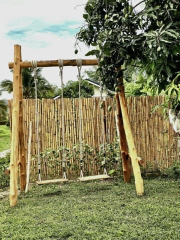 A wooden swing under a bamboo frame.