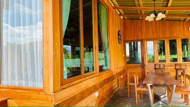 A long teak dining hall with a warm chandelier.
